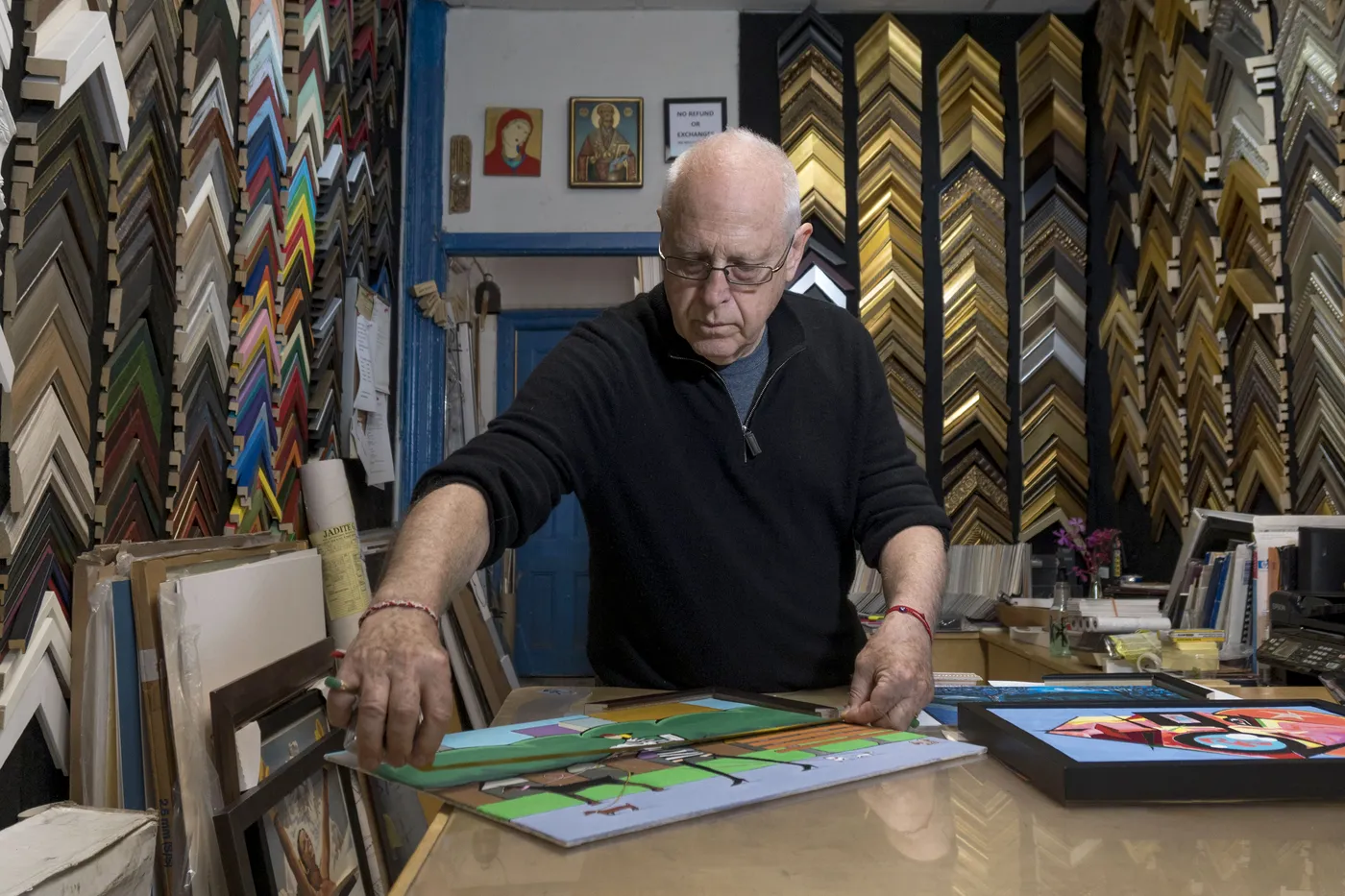 Founder comparing artworks and framing options at the workshop table